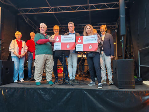 Einige Personen mit Spendenurkunden auf einer Bühne.