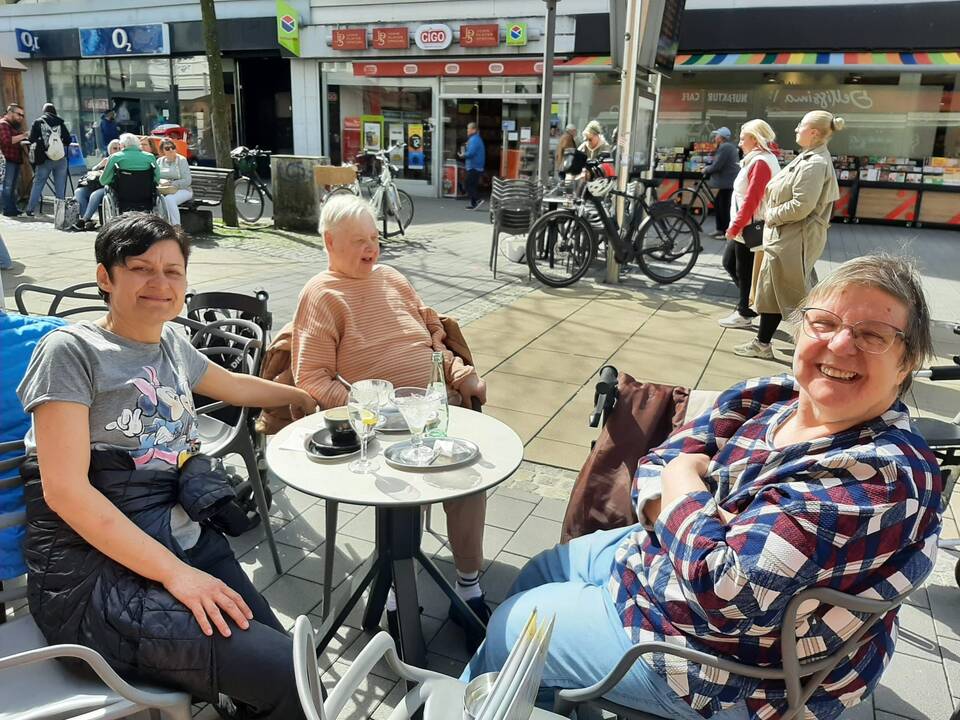 Bild sechs zeigt drei Frauen an einem Tisch vor der Eisdiele